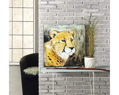 Quadratisches Wandbild mit Gepard-Motiv auf einem Konsolentisch vor einer weißen Ziegelwand neben einer Zimmerpflanze.
