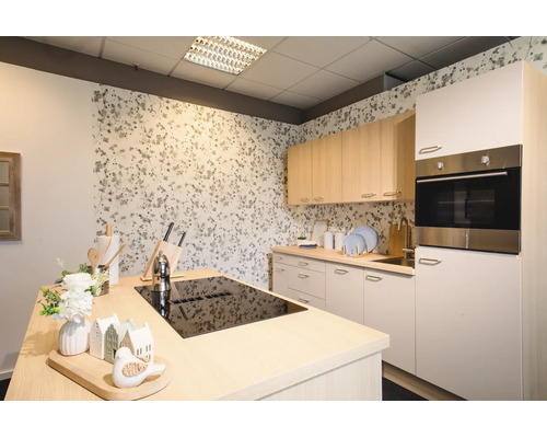Moderne, helle Küche mit Kücheninsel inklusive schwarzem Kochfeld, hellen Holz-Oberschränken, weißen Unterschränken und floraler Tapete.