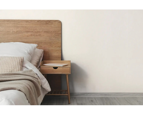 Minimalistisches Schlafzimmer mit hölzernem Kopfteil, Bett mit weißer Bettwäsche und beigefarbenem Überwurf sowie einem hölzernen Nachttisch.