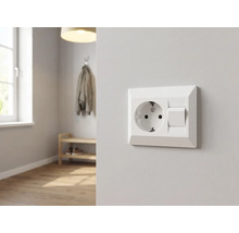 Schutzkontakt-Steckdose mit Lichtschalter Kombination an einer hellen Wand in einem modern eingerichteten, hellen Raum mit Holzboden.
