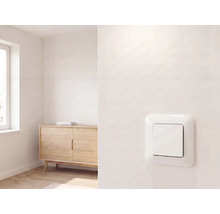 Moderner Lichtschalter an einer Wand in einem hellen, minimalistischen Raum mit Holzkommode und Fenster.