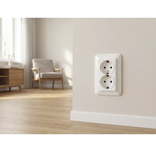 Zweifache Schutzkontakt-Steckdose an einer hellen Wand in einem modernen Wohnzimmer mit Parkettboden und Sessel.