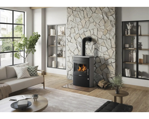 Moderner Kaminofen in einem hellen Wohnzimmer vor einer Wand mit Natursteinverkleidung, Parkettboden und Sofa.