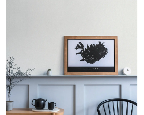Holzbilderrahmen mit einer schwarz-weißen Island-Karte auf einer Wandleiste in einem hellen, minimalistischen Raum.