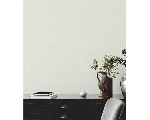 Strukturierte Vliestapete in Leinenoptik an einer Wand hinter einem dunklen Sideboard mit Dekoration und Büchern.