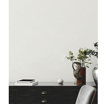 Fein strukturierte Tapete in einem hellen, organisierten Raum mit dunklem Sideboard aus Holz, einer Zimmerpflanze und Dekoration.