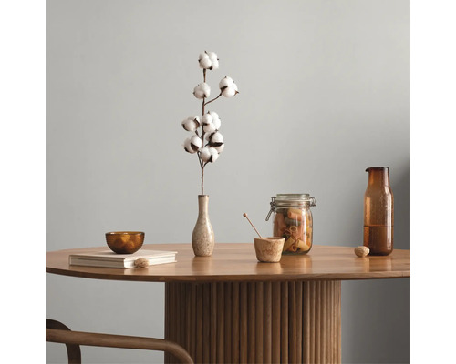 Runder Holztisch mit geriffeltem Säulenfuß, dekoriert mit einer Vase mit Baumwollzweig, einem Vorratsglas, einer Glasflasche und einem Buch.