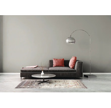 Modernes Wohnzimmer mit grauer Wand, dunklem Sofa, Bogenlampe und Marmor-Couchtisch auf gemustertem Teppich und Betonboden.