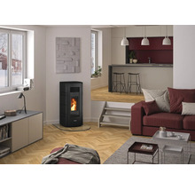 Moderner heller Wohnbereich mit schwarzem Pelletofen, brennendem Feuer, Fischgrät-Parkett, rotem Sofa und erhöhtem Küchenbereich im Hintergrund.
