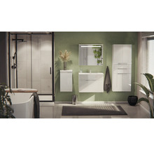 Helles, modernes Badezimmer mit weißem Waschtisch, Hochschrank, Dusche, Badewanne und Spiegel mit Beleuchtung vor einer grünen Wand.