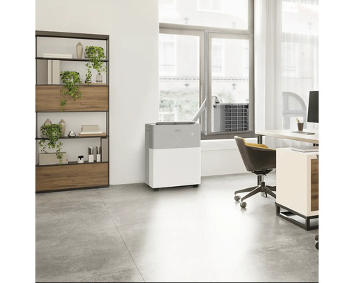 Mobiles Split-Klimagerät in einem hellen, modernen Büro mit Schreibtisch, Regal und Pflanzen. Innengerät verbunden mit Außenteil am Fenster.