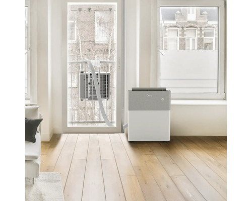 Mobile Split-Klimaanlage von Midea in hellem Zimmer. Inneneinheit mit Digitalanzeige, verbunden mit Außeneinheit am Balkongitter.