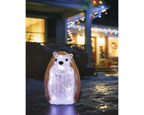 Stehender Igel aus Acryl, von innen kaltweiß leuchtend, winterliche Außendekoration in einem verschneiten Garten vor einem beleuchteten Haus.