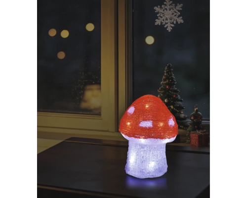 Beleuchteter LED-Deko-Fliegenpilz aus Acryl auf einem Tisch, weihnachtliche Fensterdekoration im Hintergrund.