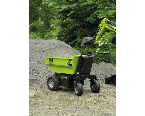 Zipper Elektro-Dumper auf einer Baustelle neben einem Sandhaufen und einem Baggerarm.