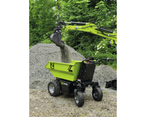 Zipper Elektro-Dumper wird im Außeneinsatz von einer Baggerschaufel mit Kies beladen.