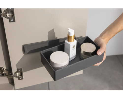 Eine graue Organizer-Box mit Kosmetikprodukten wird an einer Halterung an der Innenseite einer Schranktür eingehängt.