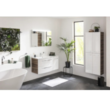 Modernes, helles Badezimmer mit weißem Waschtisch, wandhängendem Hochschrank, freistehender Badewanne und Spiegel mit Beleuchtung.