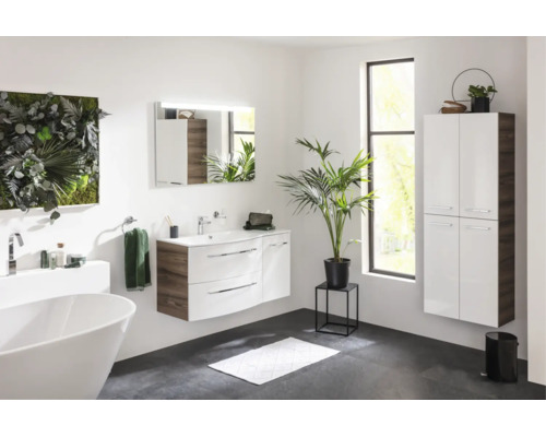 Modernes, helles Badezimmer mit weißem Waschtisch, wandhängendem Hochschrank, freistehender Badewanne und Spiegel mit Beleuchtung.