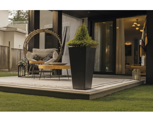 Hoher, quadratischer Pflanzkübel auf einer modernen Terrasse mit Gartenmöbeln und Teppich.