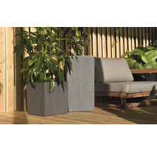Zwei graue Pflanzkübel mit Struktur auf einer Holzterrasse neben einem Loungesessel mit Polstern und einem Sichtschutzzaun aus Holz.
