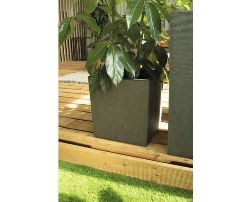 Quadratischer Pflanzkübel mit gerillter Oberfläche auf einer hellen Holzterrasse neben einer Rasenfläche.