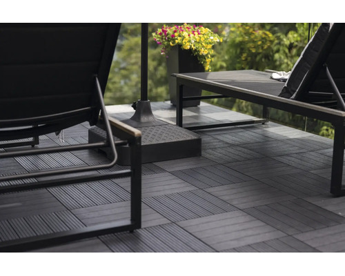 Anthrazitfarbene WPC-Terrassenfliesen mit Klicksystem auf einer Terrasse mit Gartenliegen und Sonnenschirmständer verlegt.