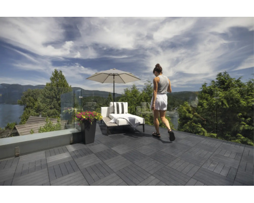Moderne Dachterrasse mit dunklen WPC-Klickfliesen, Glasgeländer, Sonnenliege, Sonnenschirm und Pflanzgefäß mit Blick auf die Natur.