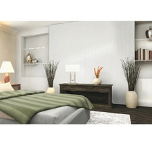 Modernes Schlafzimmer mit weißer Wandvertäfelung, dunklem Sideboard und Tischleuchten. Im Vordergrund ein Bett mit grün gestreifter Bettwäsche.