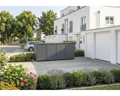 Moderne Mülltonnenbox aus Metall für vier Tonnen in einer gepflasterten Einfahrt vor einem weißen Wohnhaus mit Bepflanzung.