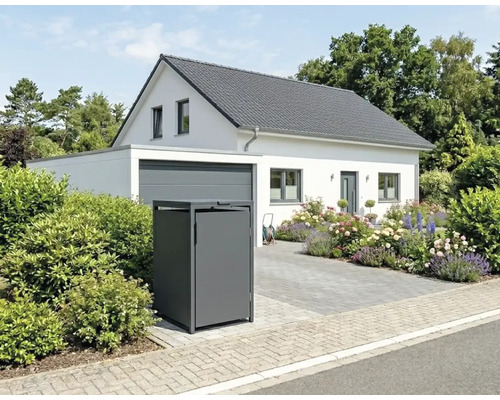 Mülltonnenbox aus Metall vor einem hellen Einfamilienhaus mit Garage, Blumengarten und gepflasterter Einfahrt.