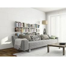 Modernes helles Wohnzimmer mit grauer Couch vor einer weißen Paneelwand mit Bücherregalen und hellem Teppich.