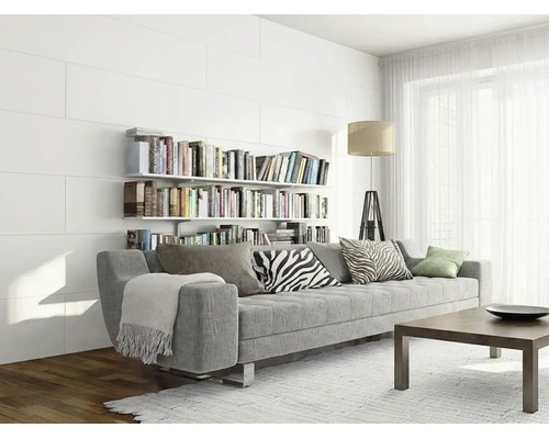 Modernes helles Wohnzimmer mit grauer Couch vor einer weißen Paneelwand mit Bücherregalen und hellem Teppich.