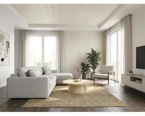 Helles, geräumiges Wohnzimmer mit hellem Ecksofa, rundem Holztisch auf einem Juteteppich, Zimmerpflanzen und großen Fenstern mit Vorhängen.