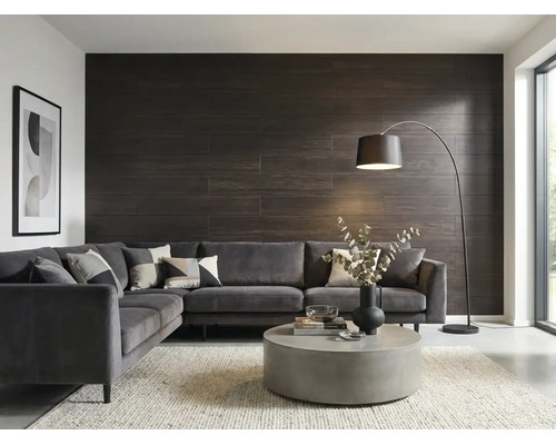 Modernes Wohnzimmer mit dunkler Wandverkleidung in Holzoptik, grauem Ecksofa aus Samt, rundem Couchtisch aus Beton und einer Bogenlampe.