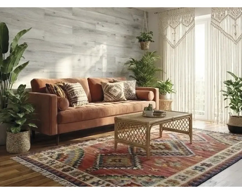 Helles Wohnzimmer im Boho-Stil mit Samtsofa, Rattan-Couchtisch und gemustertem Teppich. Grüne Zimmerpflanzen und Wandpaneele in Holzoptik.