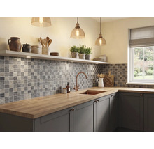 Moderne, helle Küche mit grauen Mosaikfliesen, Arbeitsplatte aus Holz, Spülbecken mit Armatur aus Kupfer und hängenden Glaspendelleuchten.