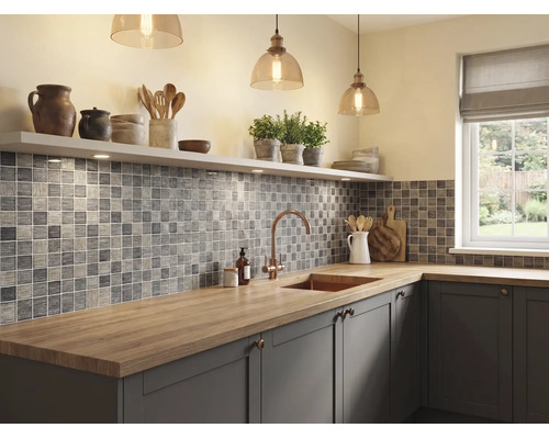 Moderne, helle Küche mit grauen Mosaikfliesen, Arbeitsplatte aus Holz, Spülbecken mit Armatur aus Kupfer und hängenden Glaspendelleuchten.