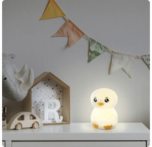 Leuchtendes LED-Nachtlicht in Pinguinform auf einem weißen Möbelstück im Kinderzimmer neben Holzspielzeug und einer Wimpelkette.