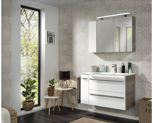 Modernes Badezimmer mit Waschtischunterschrank in Weiß und Holzoptik, Waschbecken und dreitürigem Spiegelschrank mit LED-Beleuchtung.