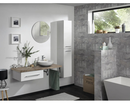 Modernes Badezimmer mit hängendem Waschtisch, weißem Hochschrank, rundem Spiegel und freistehender Badewanne vor grauen Fliesenwänden.