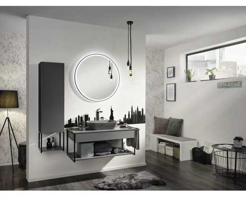 Modernes Badezimmer mit rundem LED-Spiegel, grauem Waschtisch, Aufsatzbecken, Hochschrank, Skyline-Wandtattoo und industrieller Beleuchtung.