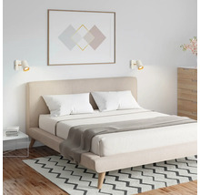 Modernes Schlafzimmer mit Doppelbett, beige gepolstertem Kopfteil und zwei weißen Wandstrahlern über dem Bett.