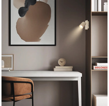 Moderne Wandleuchte als Leselampe an einem Regal über einem Schreibtisch, minimalistischer Einrichtungsstil mit abstrakter Kunst.