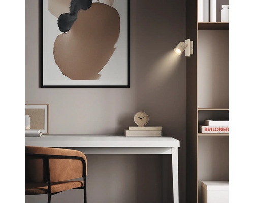 Moderne Wandleuchte als Leselampe an einem Regal über einem Schreibtisch, minimalistischer Einrichtungsstil mit abstrakter Kunst.