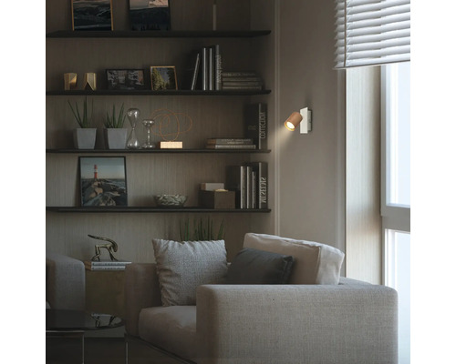 Moderne Wandleuchte mit Holzschirm in einem wohnlich eingerichteten Zimmer mit Sofa, Wandregalen und warmem Licht.
