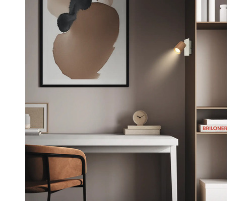 Moderner Arbeitsplatz mit weißem Schreibtisch, braunem Stuhl und Regal. Eine Wandleuchte aus Holz am Regal beleuchtet den minimalistischen Raum.