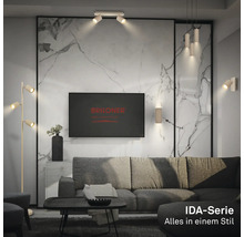 Modernes Wohnzimmer mit Lampen der Briloner IDA-Serie: Stehleuchte, Deckenstrahler, Pendelleuchte und Wandleuchten vor einer Wand in Marmoroptik.