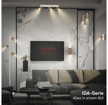 Wohnzimmer mit Lampen der Briloner IDA-Serie, darunter Deckenstrahler, Pendel-, Steh- und Wandleuchten vor einer Wand in Marmoroptik.