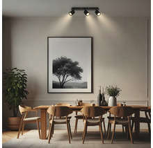 Dreiflammiger Deckenstrahler in einem modernen Esszimmer über einem Holztisch mit Stühlen und großem Wandbild.